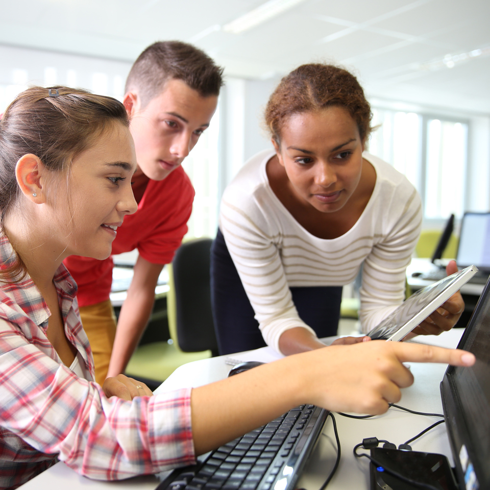 two female and one male participant surround a computer